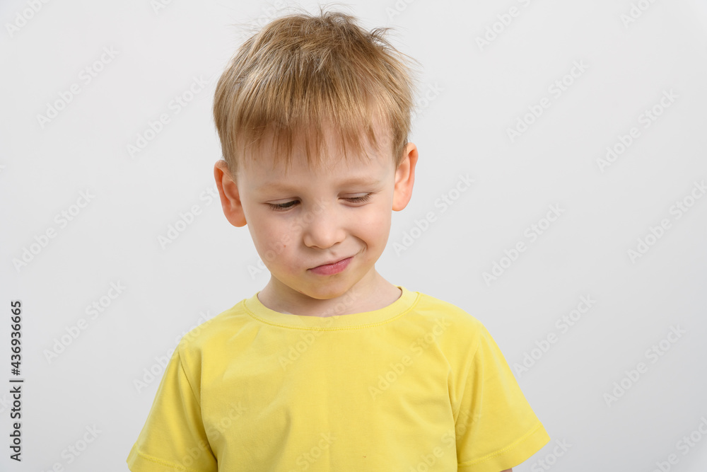 portrait of a little boy in a yellow t-shirt on a white background. sly face portrait of a little boy in a yellow t-shirt on a white background. sly face