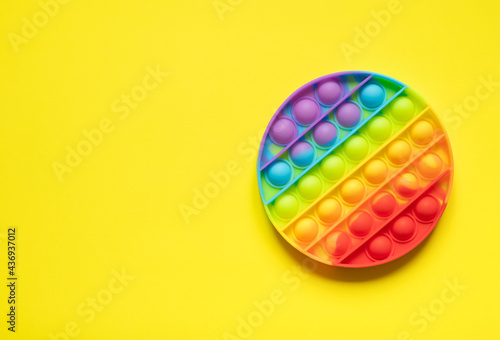 modern bright toy antistress pop it. rainbow play on yellow background with copy space