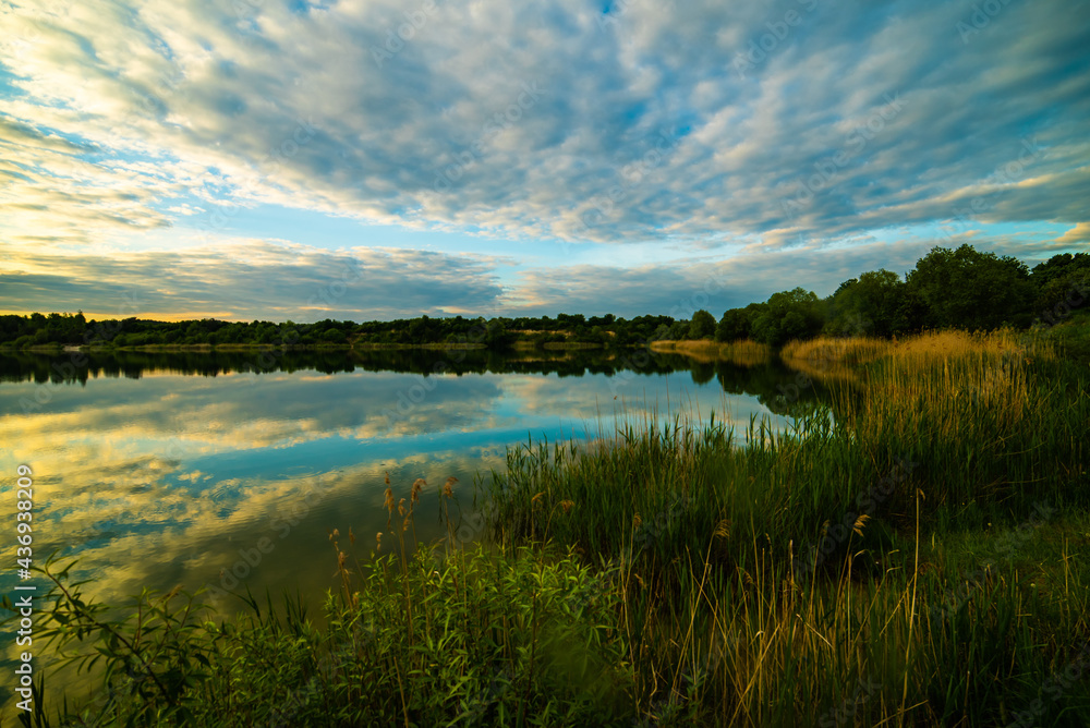 sunset at coast of the lake. Nature landscape.  reflection, blue sky and yellow sunlight. landscape during sunset.