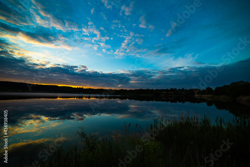 Fototapeta Naklejka Na Ścianę i Meble -  sunset at coast of the lake. Nature landscape.  reflection, blue sky and yellow sunlight. landscape during sunset.