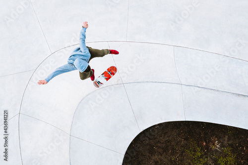 Aerial view of professional skateboarder jumping and doing kick flip trick in urban skate park in Kaunas, Lithuania.