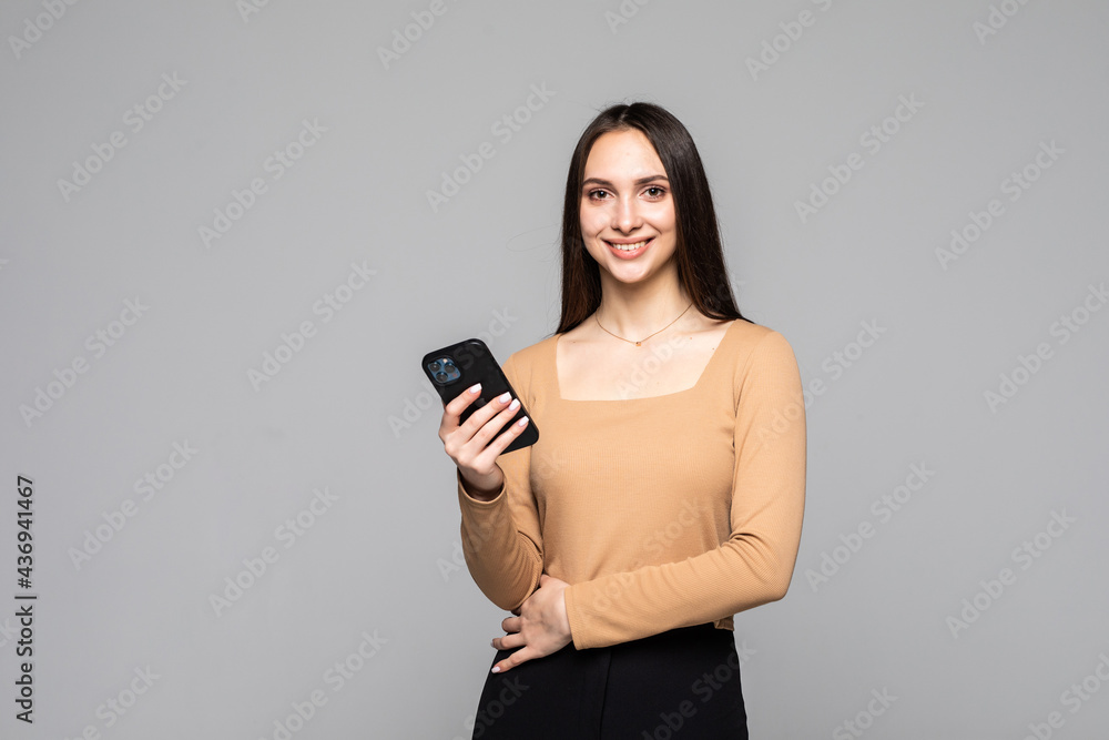 Naklejka premium Content woman use phone, isolated over grey background