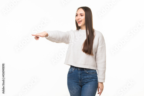 Beautiful young woman pointing to somewhere over a white background