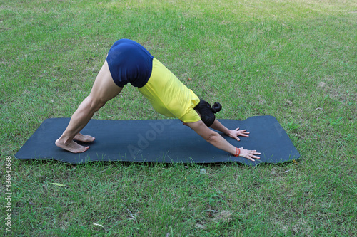 A woman practices yoga on the lawn in the park