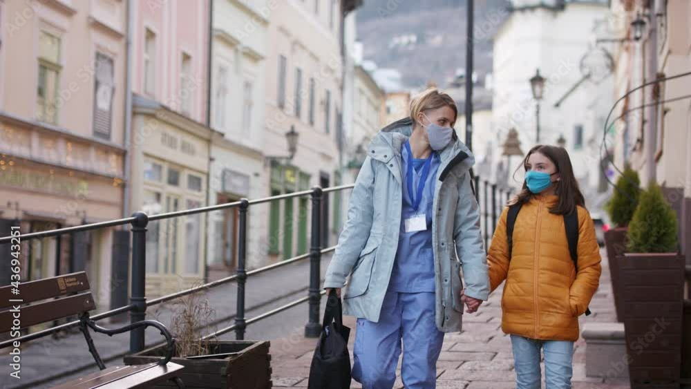 Woman healthcare worker outdoors on the way to work with schoolgirl daughter, coronavirus concept. Woman healthcare worker outdoors on the way to work with schoolgirl daughter, coronavirus concept.