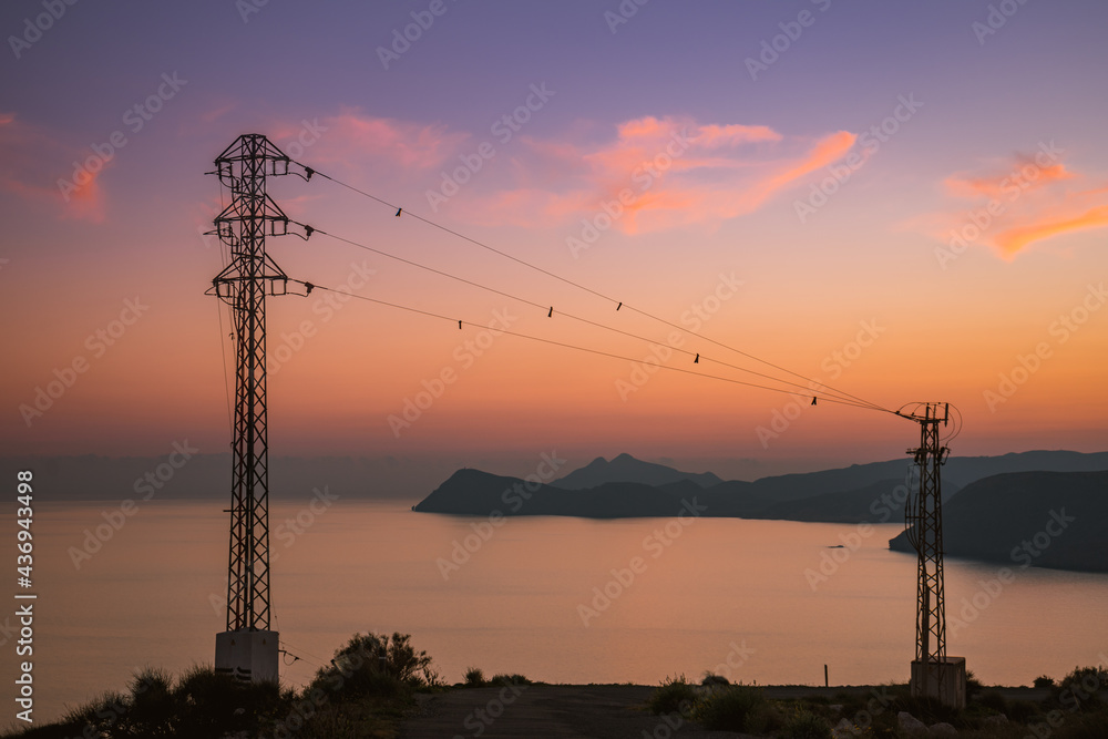 High voltage towers on coast at sunset