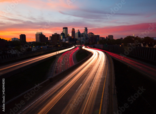 Minneapolis skyline at sunset from the pedestrian bridge with light trails on highway