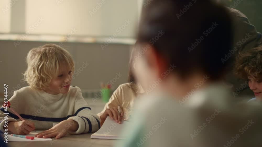 Teacher talking with students at round table in classroom. Pupils having lesson Teacher talking with students at round table in classroom. Pupils having lesson