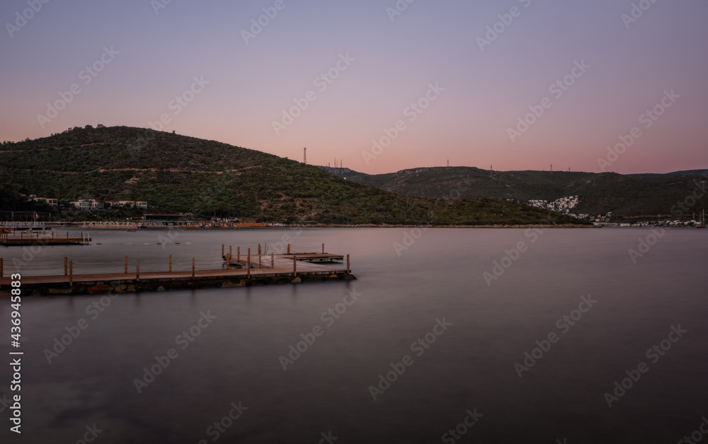 sunset over bay in Aegean sea. Torba, Bodrum, Turkey. October 2020. Long exposure picture with pier, jetty