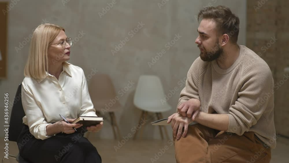 Medium shot of female psychologist and depressed man having conversation sitting at mental health support centre Medium shot of female psychologist and depressed man having conversation sitting at mental health support centre