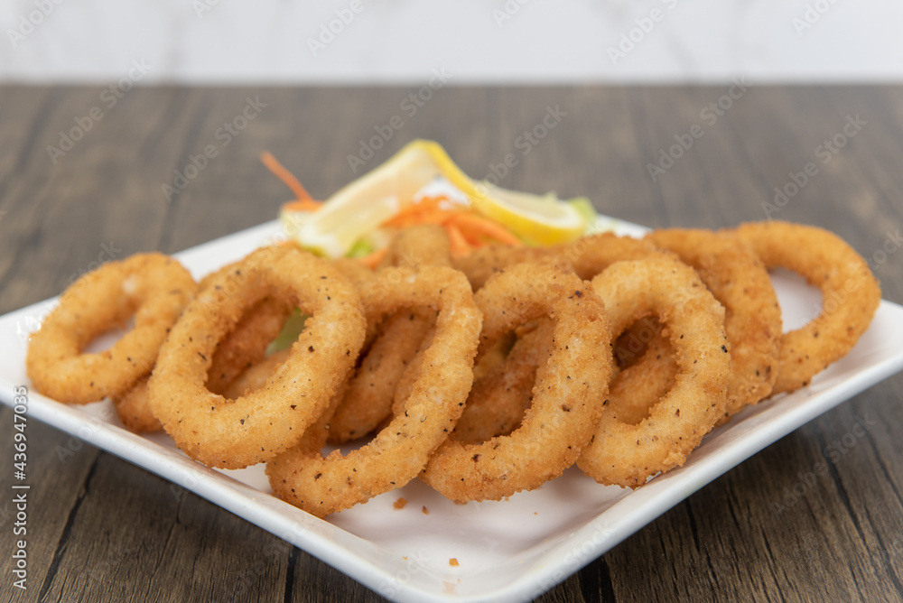 Deep fried calamari rings arranged on a plate as an appetizer for your meal Deep fried calamari rings arranged on a plate as an appetizer for your meal
