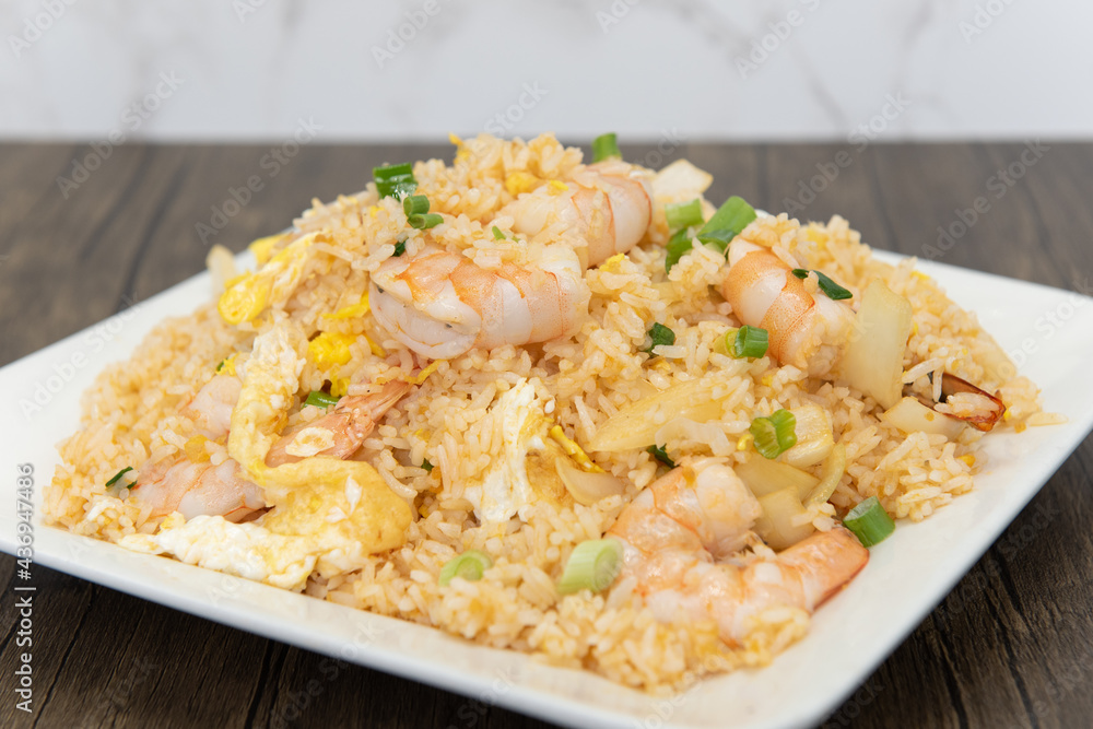 Huge pile of fried rice topped with shrimp and vegetables on.a plate to fulfill that spicy craving