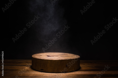 empty circular wooden cutiing board with smoke float up on dark background © Thitiwat.Day