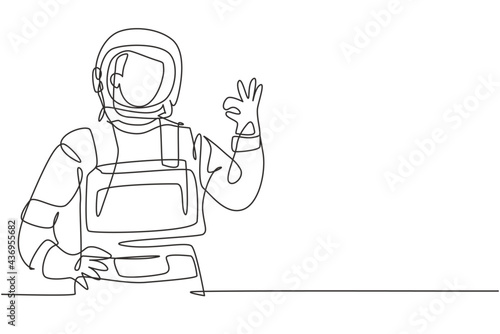 Single one line drawing of male astronauts with gesture okay wearing spacesuits to explore outer space in search mysteries of universe. Modern continuous line draw design graphic vector illustration
