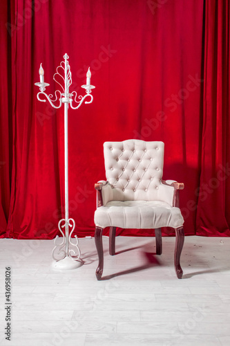 White luxury chair, vintage candles next to it, and it's all on a red background