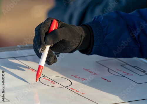 A coach draws up a play on a White Board on the sidelines of a Football/Soccer game