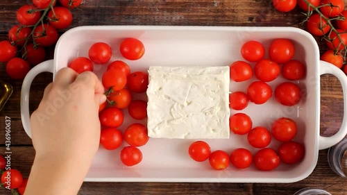 Making baked feta pasta with cherry tomatoes, herbs and olive oil, trendy food recipe photo