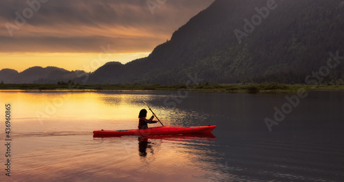 Adventure Caucasian Adult Woman Kayaking in Red Kayak surrounded by Canadian Mountain Landscape. Sunset Sky Art Render. Widgeon Valley, Pitt Meadows, Vancouver, British Columbia, Canada.