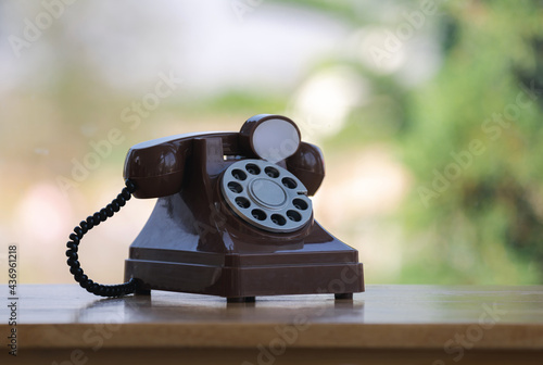 old retro style of finger dial telephone on wooden table bar with green nature bokeh background