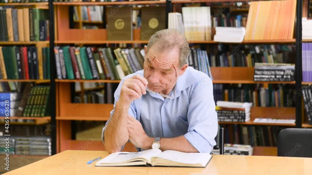 Smart senior man reading a book in the library Smart senior man reading a book in the library