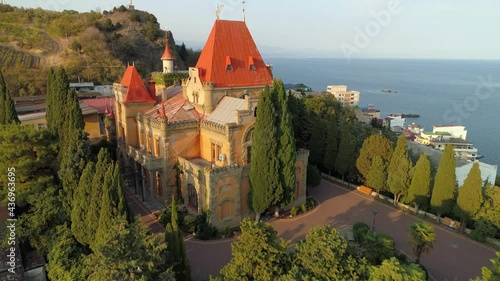 Drone forward incredible stone medieval castle manor of princes Crimea historical landmark. Red roof, art nouveau style. Romantic Alushta cityscape at sunset. Travel tourism resort Russia. Black sea photo