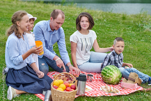 Happy family at a picnic. Picnic in the meadow or park. Young friends and their children in nature