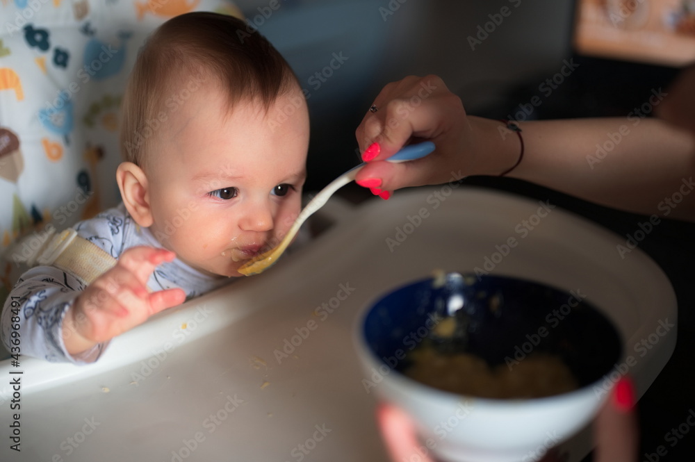 Woman's hand feeding her baby son with spoon Woman's hand feeding her baby son with spoon