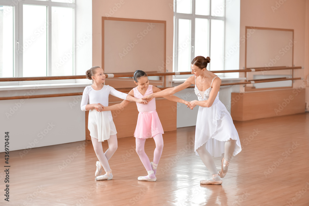 Naklejka premium Little ballerinas training with coach in dance studio