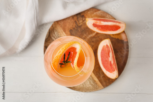 Glass of tasty grapefruit cocktail on light wooden background