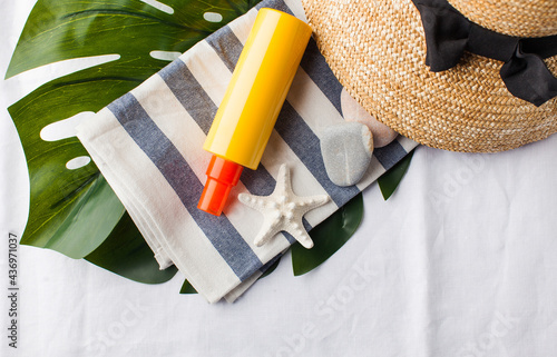 Summer background. Hat, seashells, sunscreen on a white towel. Copy space. photo