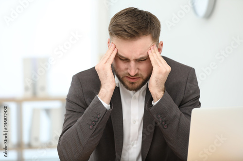 Valokuva Young man suffering from migraine in office