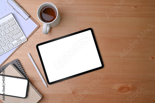 Top view digital tablet and mobile phone with white screen on wooden background.