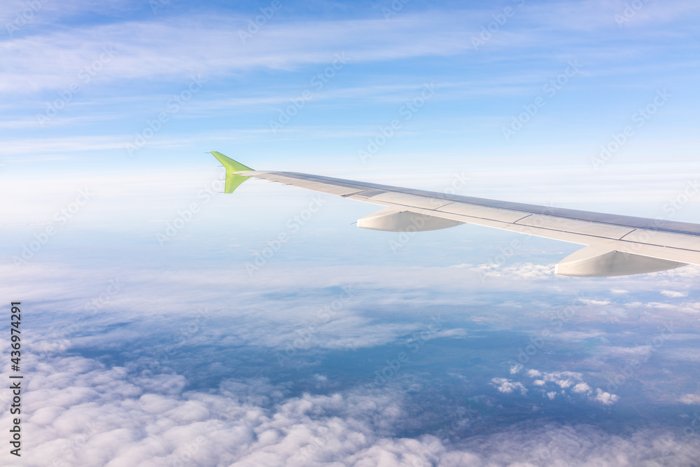 View from the airplane window at a beautiful blue sunrise and the airplane wing above the clouds. View from the airplane window at a beautiful blue sunrise and the airplane wing above the clouds.