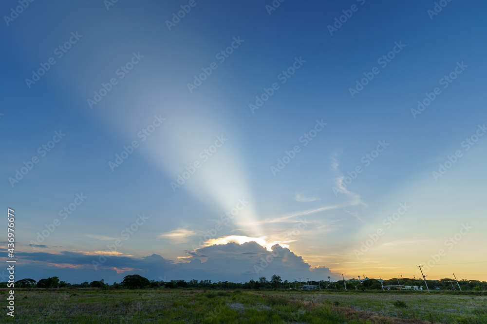 Twilight blue bright and orange with sunbeams shining through dramatic white clouds sunset sky in countryside or beach colorful cloudscape texture air background.