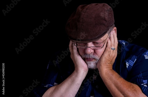Portrait of Caucasian senior man desperately thinking about life problems in the darkness