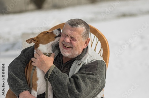 Cute basenji dog whisper its master love you while sitting on the hands of Caucasian senior man  at winter season