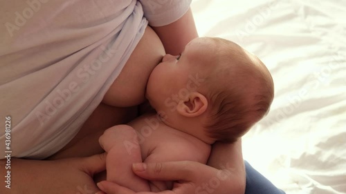 Mother breastfeeding baby at home. Mom nursing infant nurturing. Portrait of Child suckling milk from breast. Authentic shot of mother is breastfeeding her newborn baby. Close Up. Concept of maternity