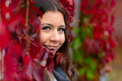 young smilling woman upon a wall of red ivy leaves