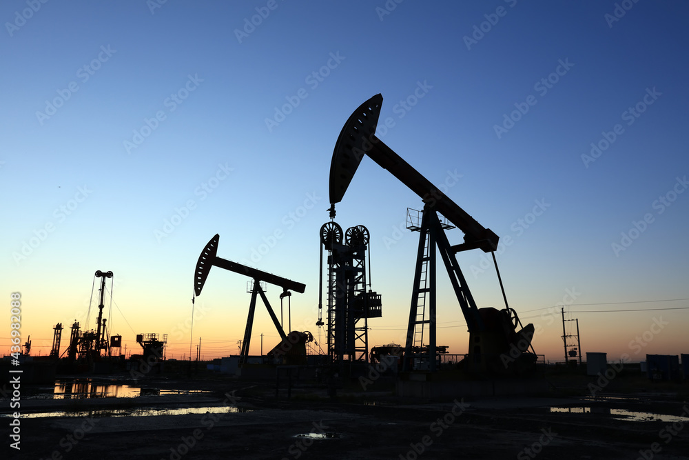 In the evening, oil pumps are running, Silhouette of beam pumping unit In the evening, oil pumps are running, Silhouette of beam pumping unit