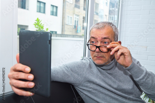 man with presbyopia or myopia surprised looking at the digital tablet photo