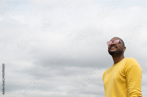 Black man looking at the horizon in a park with glasses