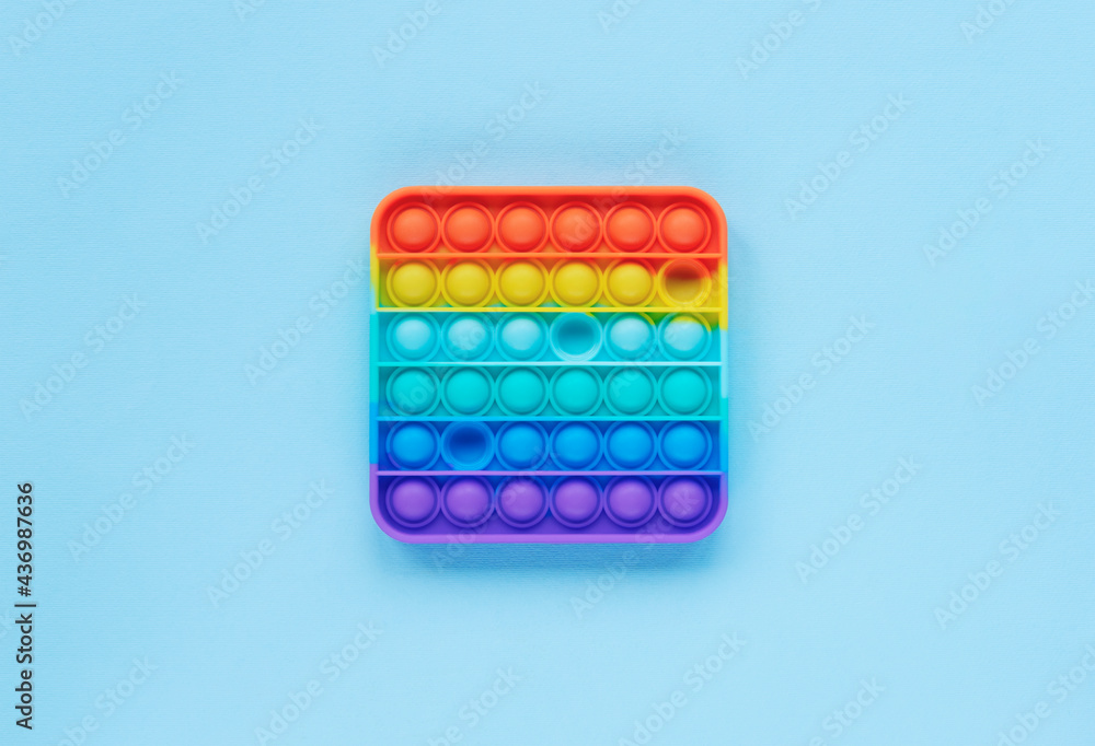 Colorful poppit game on blue background. Pop it fidget toy. Top view, flat lay Colorful poppit game on blue background. Pop it fidget toy. Top view, flat lay