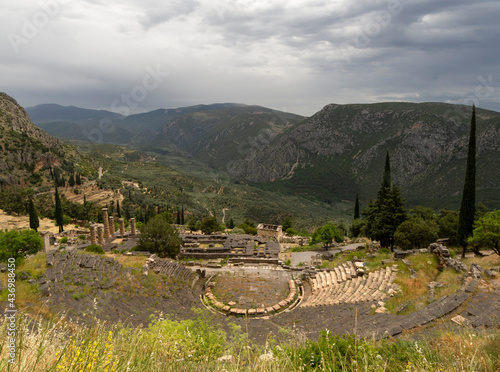 Panoramic view on ancient theater and temple of Apollo with columns in Delphi against the background of mountains and the sky with clouds in Greece photo