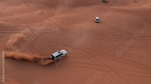 AERIAL. Column of white cars travelling in sand desert. © skymediapro