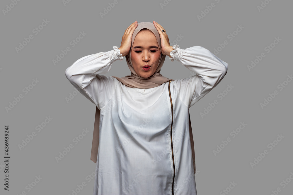 Woman wearing hijab holding head with both hands while closing her eyes Woman wearing hijab holding head with both hands while closing her eyes