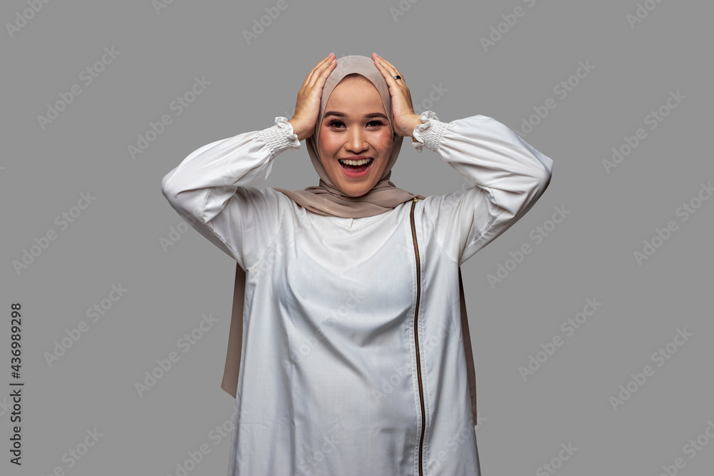 Indonesian woman in hijab holding head while smiling Indonesian woman in hijab holding head while smiling