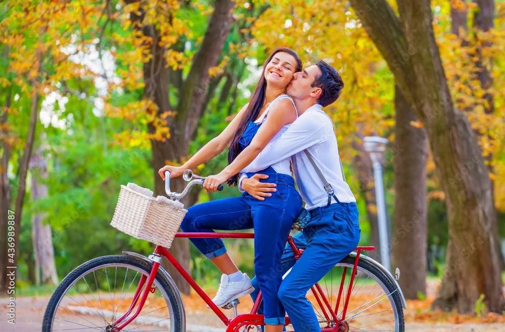 Obraz premium Teen couple with retro bike kissing in the park in autumn time
