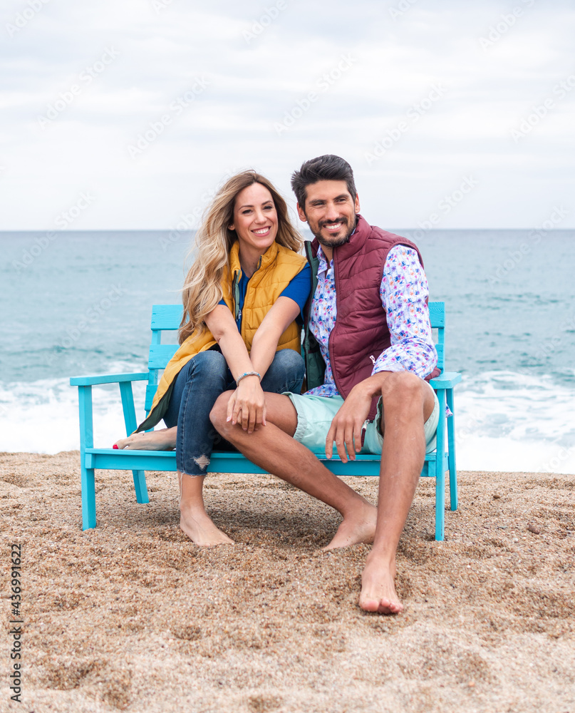 Content multiethnic couple resting on bench on sea shore Content multiethnic couple resting on bench on sea shore
