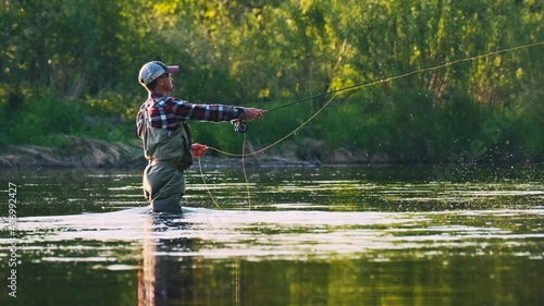 Fly fishing. Fly fisherman casts the line on the river. Angler stands in the river and casts the fly photo