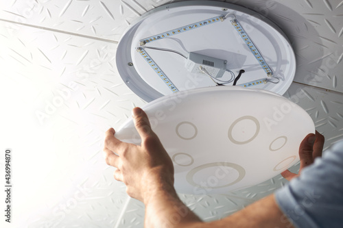 An electrical technician changes a low-consumption LED lamp into a residential electrical system, Closes the lid